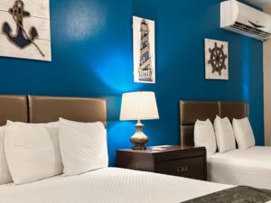 Bedroom with blue and tan walls, tile flooring, two queen beds with white bedding, and dark wooden nightstand