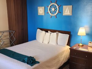 Bedroom with blue and tan walls, tile flooring, dark wooden furniture, and white bedding