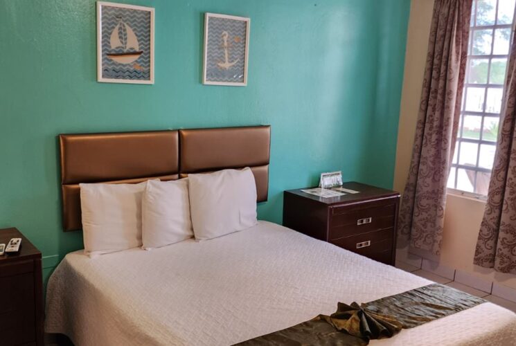 Bedroom with turquoise and tan walls, tile flooring, dark wooden furniture, and white bedding