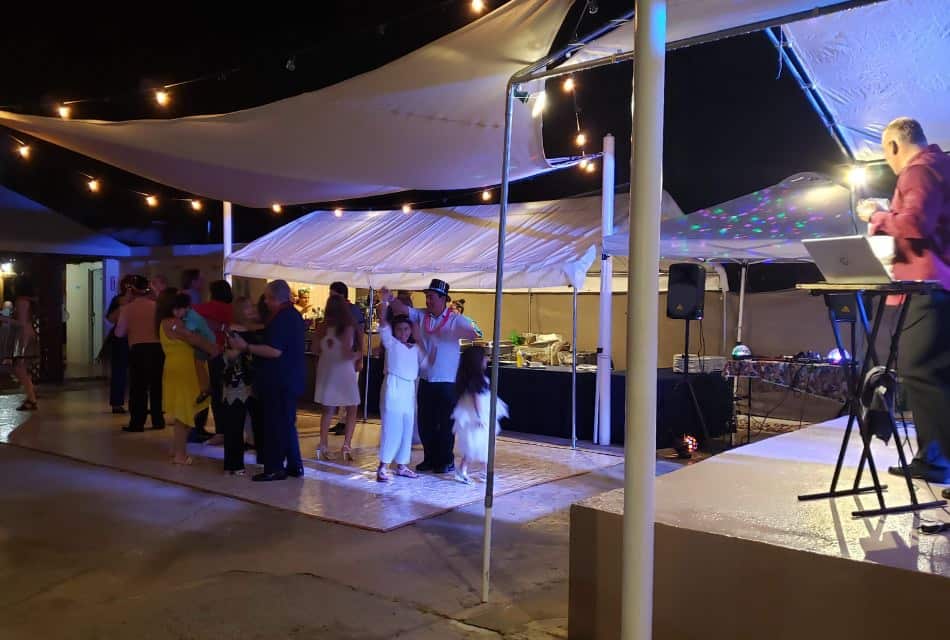 Exterior patio set up for a group event with people dancing to a band at night